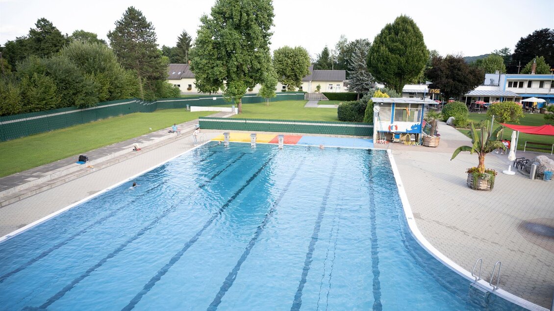 Ein Schwimmbecken mit klarem Wasser und mehreren Bahnen. Im Hintergrund sind grüne Bäume und eine gepflegte Umgebung zu sehen. | © Schilcherland Steiermark