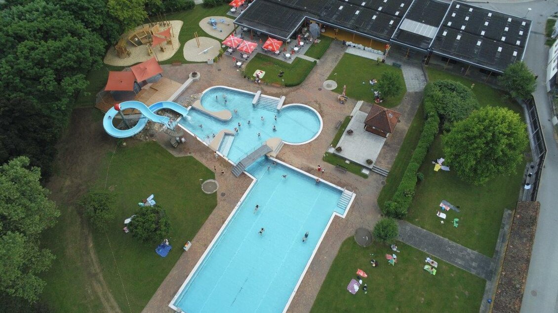 Ein weitläufiges Freibad mit einem großen Becken und einer Rutsche. Rundherum befinden sich Liegewiesen und Spielbereiche für Kinder. | © Erlebnisbad Pöllau