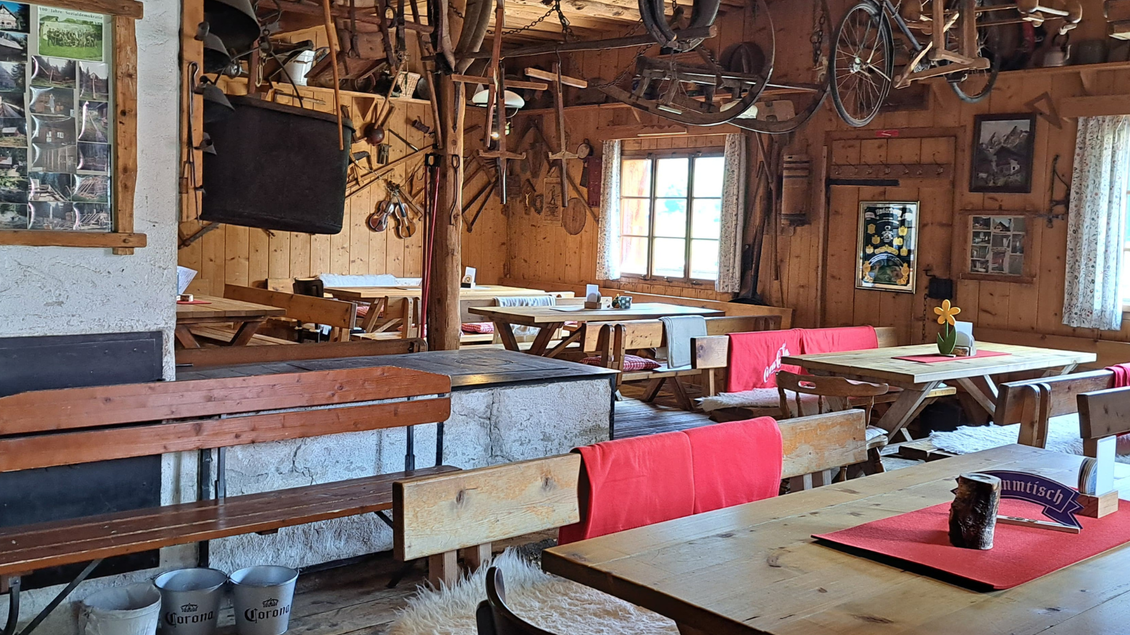 Ein gemütliches Restaurant mit Holzmöbeln und traditioneller Dekoration. An den Wänden hängen alte Landwerkzeuge und Fotos. | © Eselalm