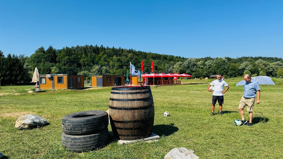 Die Fußballgolf-Anlage im Grünen zeigt ein paar Hindernisse und im Hintergrund ein kleines Holzhaus zum Anmelden und Rasten. | © Tourismusverband Oststeiermark