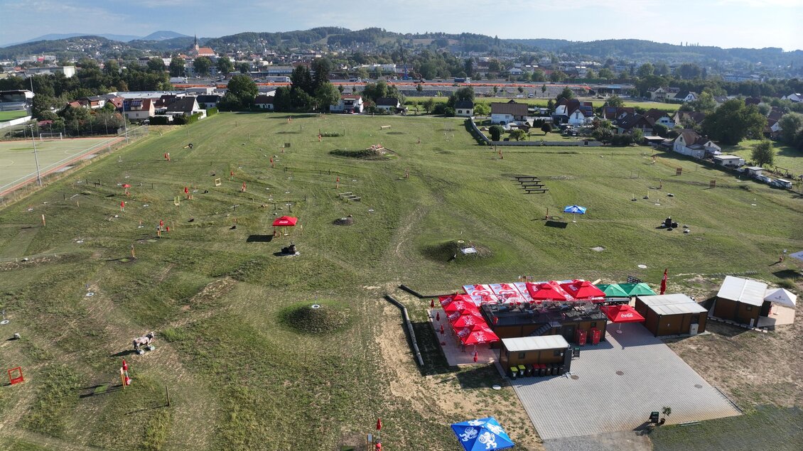 Hier sieht man von oben fotografiert die Größe des Areals - 5 Hektar - und die unterschiedlichen Ausstattungen des Parcours mit diversen Hindernissen sowie den Bereich zum Rasten und Anmelden, beschattet mit roten Sonnenschirmen. | © Tourismusverband Oststeiermark