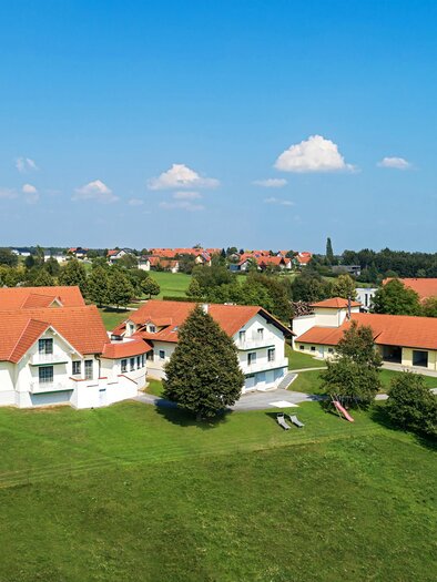 Eine schöne Landschaft mit mehreren Häusern und rotem Dach. Umgeben von grünen Wiesen und blauem Himmel. | © Fam. Fiedler