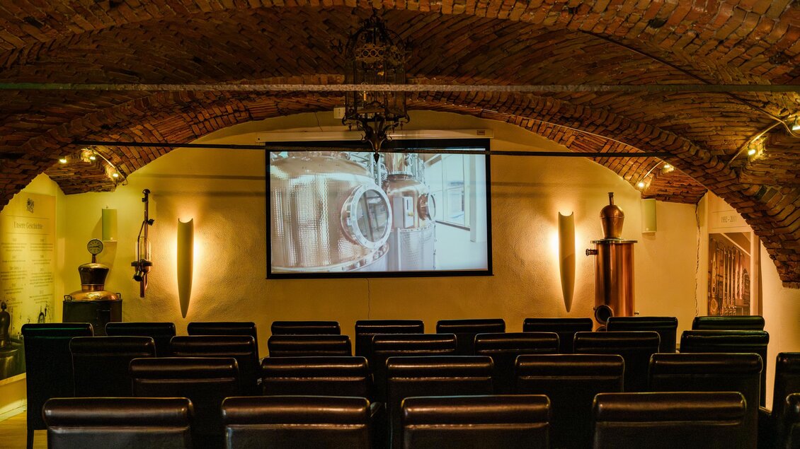 <p>Filmraum der Feindestillerie Hochstrasser in Mooskirchen mit Sitzreihen, Leinwand und historischer Gewölbedecke. | © (c) Region Graz - Mias Photoart