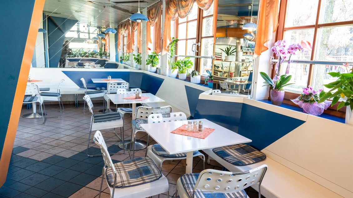 Ein modernes Café mit hellen Fenstern und Pflanzen. Die Tische sind sauber und gut dekoriert, ideal für einen gemütlichen Aufenthalt. | © Stephan Friesinger