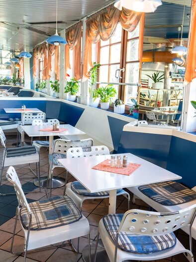 Ein modernes Café mit hellen Fenstern und Pflanzen. Die Tische sind sauber und gut dekoriert, ideal für einen gemütlichen Aufenthalt. | © Stephan Friesinger