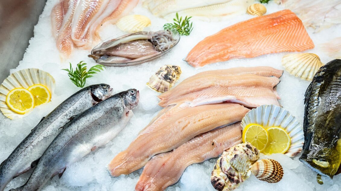 Frischer Fisch und Meeresfrüchte auf Eis liegend. Dazu geschnittene Zitrone und Muscheln. | © Stephan Friesinger