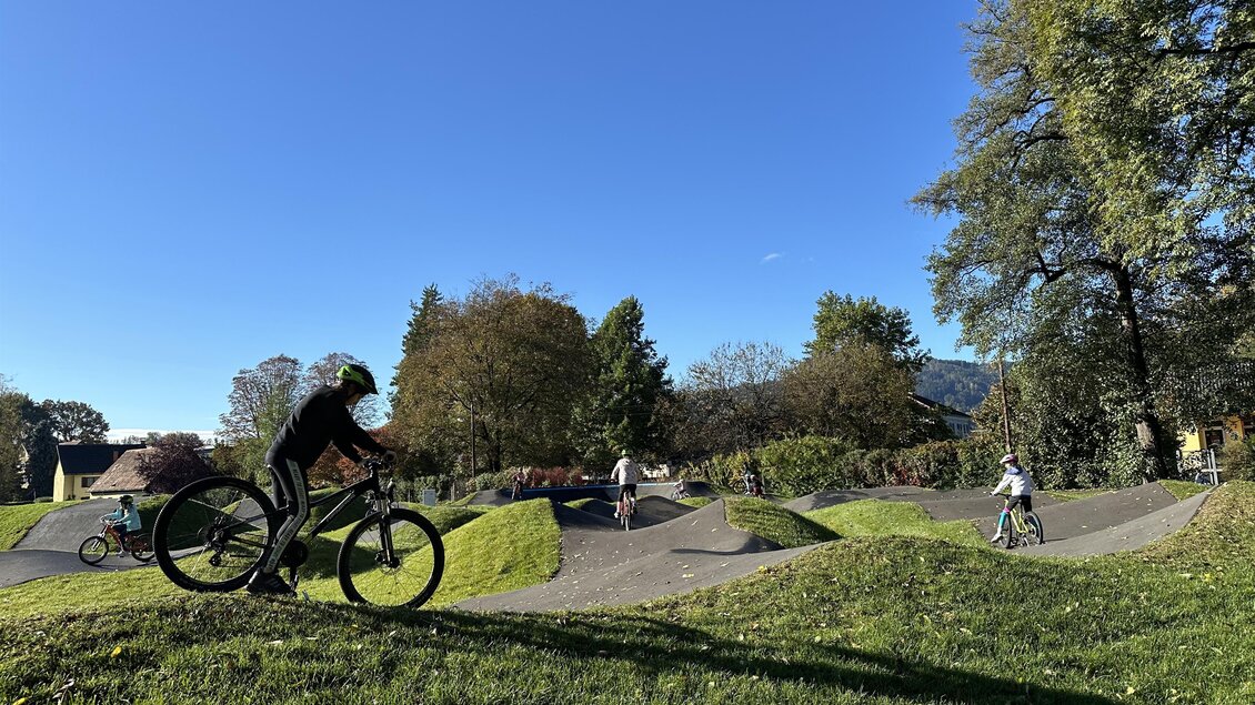 Ein BMX-Park mit mehreren Hügeln und Bodenwellen. Kinder fahren Fahrrad und genießen einen sonnigen Tag im Freien. | © Stadtgemeinde Deutschlandsberg | E. Kleindienst