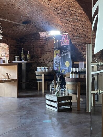 Ein gemütlicher Innenraum mit hohen Decken und Holzmöbeln. Im Hintergrund sind Regale mit Produkten und eine Theke zu sehen. | © weingut wieser
