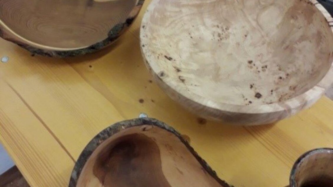 Handgefertigte Holzschalen in verschiedenen Formen und Größen auf einem Tisch. Die Schalen zeigen die natürliche Maserung und Textur des Holzes.