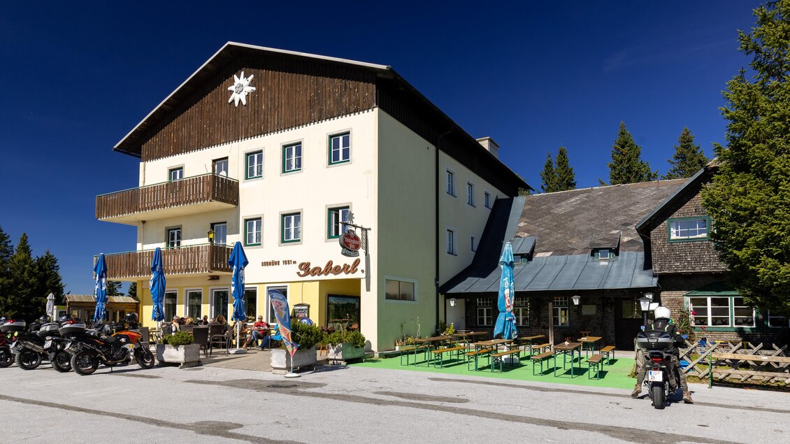 Gaberlhaus auf der Stubalpe mit Gastgarten, Terrasse und abgestellten Motorrädern vor dem Gebäude. | © TV Region Graz - Harry Schiffer