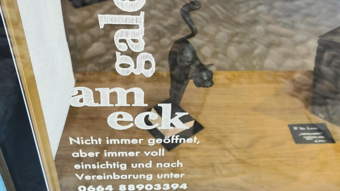 Eine Galerie mit einer Skulptur im Vordergrund. Der Schriftzug informiert über die Öffnungszeiten und Kontaktmöglichkeiten. | © Jörg Roskaric