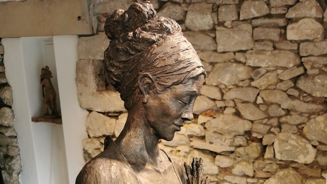 Eine elegante Skulptur einer Frau steht vor einer steinenden Wand. Die Details der Statue zeigen eine ruhige und nachdenkliche Ausstrahlung. | © Jörg Roskaric