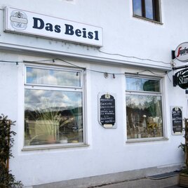 Ein Restaurant mit dem Namen "Das Beisl" ist an einer weißen Wand zu sehen. Die Fenster sind gut sichtbar und es gibt eine kleine Tafel neben dem Eingang. | © Gemeinde Gratkorn - Gasser