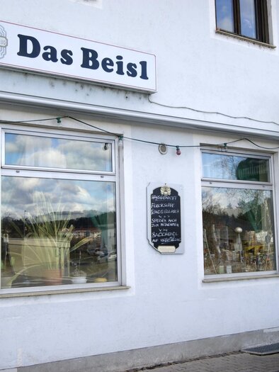 A restaurant named "Das Beisl" is visible on a white wall. The windows are clearly visible and there is a small board next to the entrance. | © Gemeinde Gratkorn - Gasser