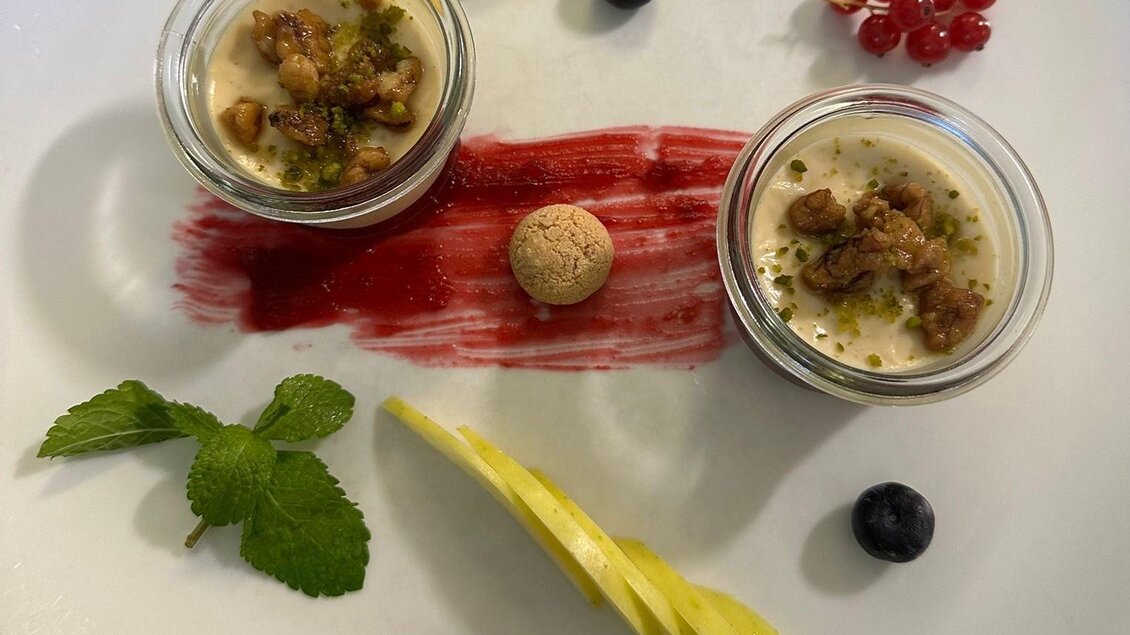 Ein schön angerichtetes Dessert auf einem Teller. Es gibt zwei Gläser mit Pudding, frische Früchte und eine dekorative Sauce. | © Gasthaus Bachwirt