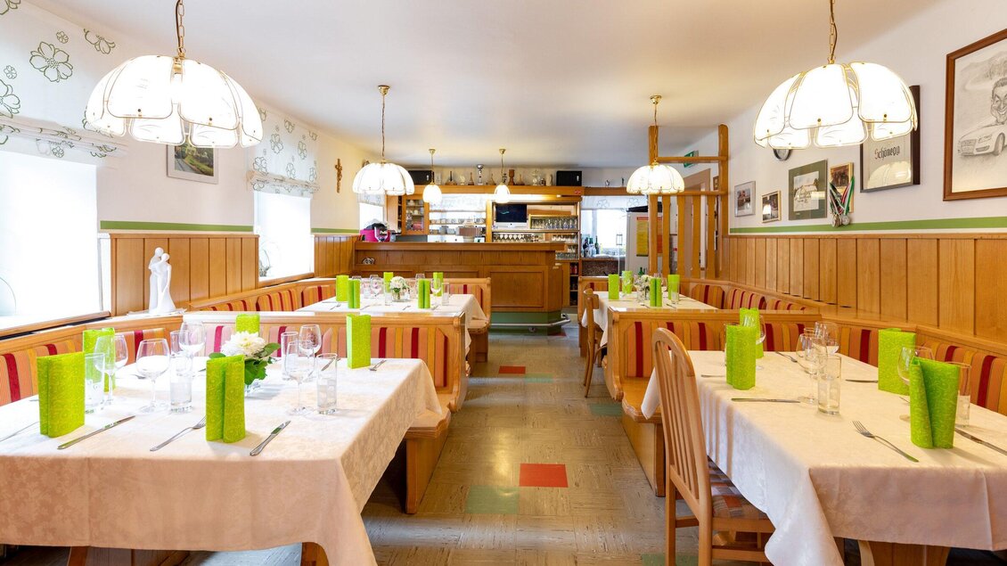 Ein gemütliches Restaurant mit Holzverkleidung und hellen Lampen. Die Tische sind elegant gedeckt und mit grünen Dekorationen ausgestattet. | © TV Region Graz - Harry Schiffer