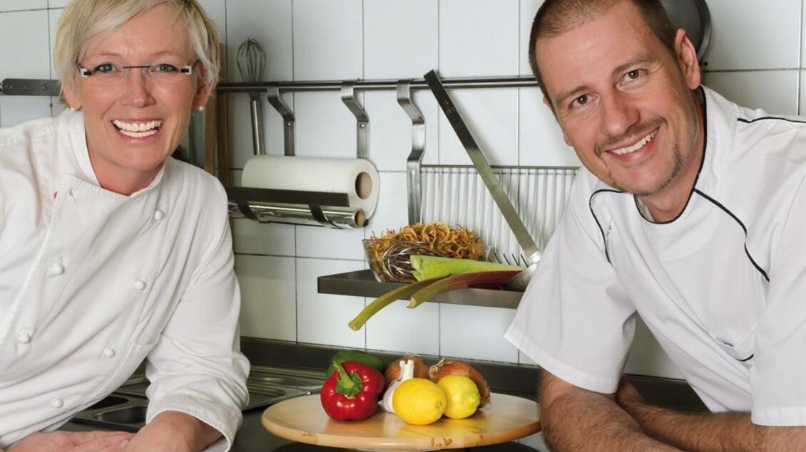 Zwei Personen in Kochkleidung präsentieren eine Speise in der Küche des Gasthauses Jägerwirt in Graden. | © Familie Wipfler