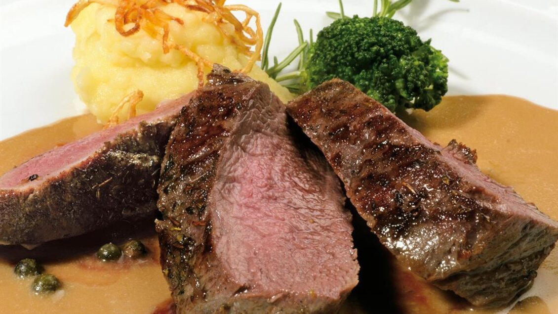 <p>Rosa gebratenes Fleisch mit Sauce, Kartoffelbeilage und Brokkoli auf einem Teller im Gasthaus Jägerwirt in Graden.</p> | © Familie Wipfler