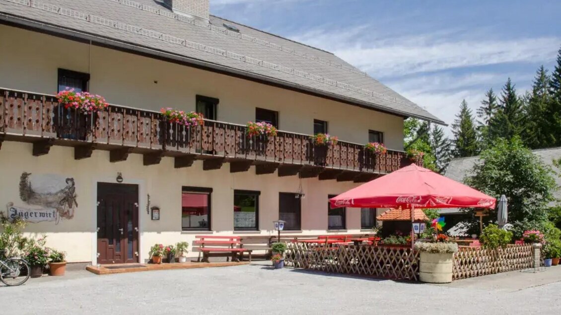 Traditionelles Gasthaus Jägerwirt in Semriach mit Balkon, Blumenschmuck und Gastgarten vor dem Gebäude. | © Fam. Greimel
