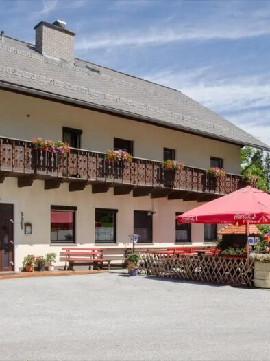 Traditional inn Jägerwirt in Semriach with balcony, floral decorations, and outdoor dining area in front of the building. | © Fam. Greimel