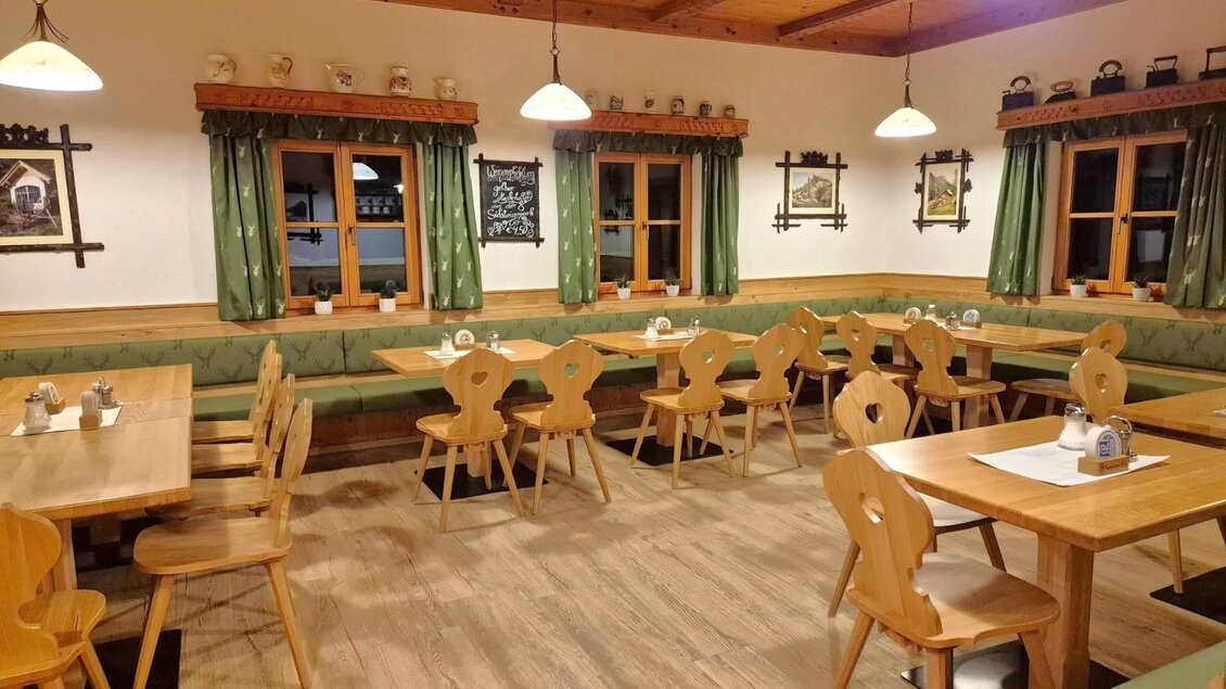 Ein gemütliches Restaurant mit Holzstühlen und Tischen. Die Wände sind in warmen Farben gestrichen und es gibt grüne Vorhänge an den Fenstern. | © Gasthaus Murbodenhüttl