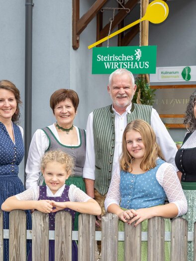 Host family in Styrian traditional dress in front of the entrance of the inn Platzwirt in Graden. | © Region Graz, Harry Schiffer