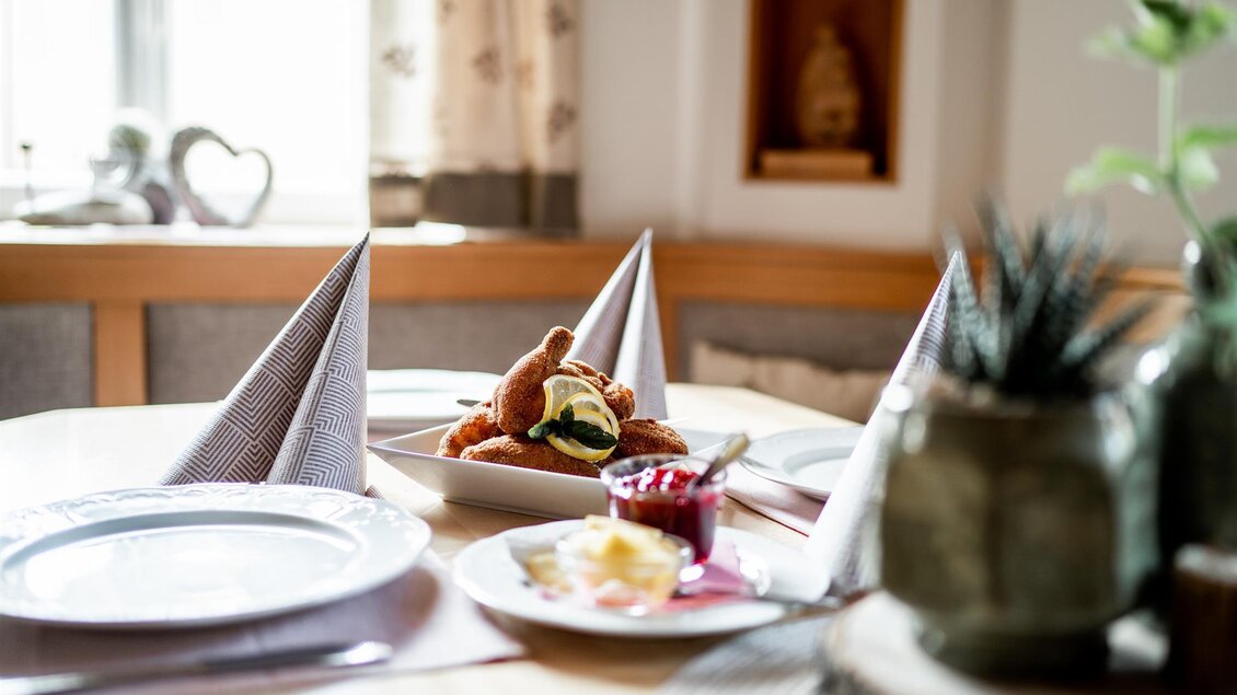 Tisch im Gastraum des Platzwirts Graden mit serviertem Schnitzel, Preiselbeeren und Zitronenscheiben.  | © Platzwirt_KerstinFotografie