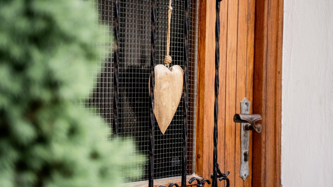 <p>Ein Holzherz als Türdeko am Eingang des Platzwirts in Graden mit Holztür und Gitter.  | © Platzwirt_KerstinFotografie