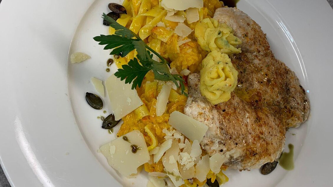 Man sieht als Hauptspeise ein Hühnerfilet mit Kürbisbandnudeln am weißen Teller serviert.  | © Gasthaus Strobl
