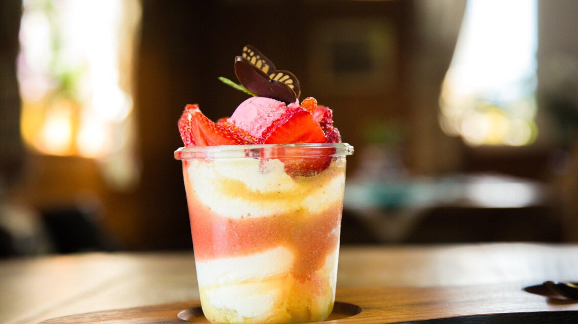 <p>Ein Glas mit frischem Dessert aus cremigem Joghurt, frischen Erdbeeren und einer Schokoladenverzierung, serviert in einem eleganten, klaren Becher im Gasthaus Tax in Bärnbach.</p> | © Geopho