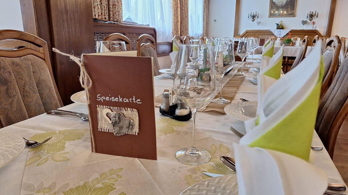 Ein elegant gedeckter Tisch mit einem Menü in der Mitte. Die Atmosphäre ist einladend und gemütlich. | © Gasthaus Unterdechler