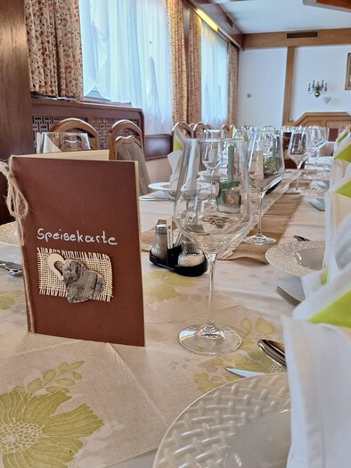 Ein elegant gedeckter Tisch mit einem Menü in der Mitte. Die Atmosphäre ist einladend und gemütlich. | © Gasthaus Unterdechler