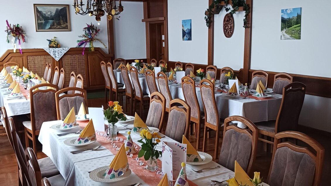 Ein festlich gedeckter Speisesaal mit mehreren Tischen. Die Tische sind mit Blumen und kleinen Hüten dekoriert. | © Gasthaus Unterdechler
