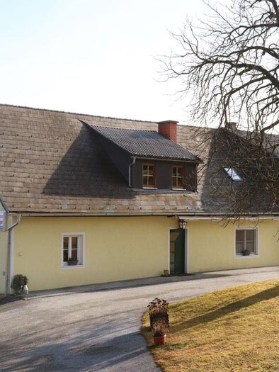 Yellow building of the inn Wartinger in Edelschrott with access road and large tree | © Steirische Rucksackdörfer