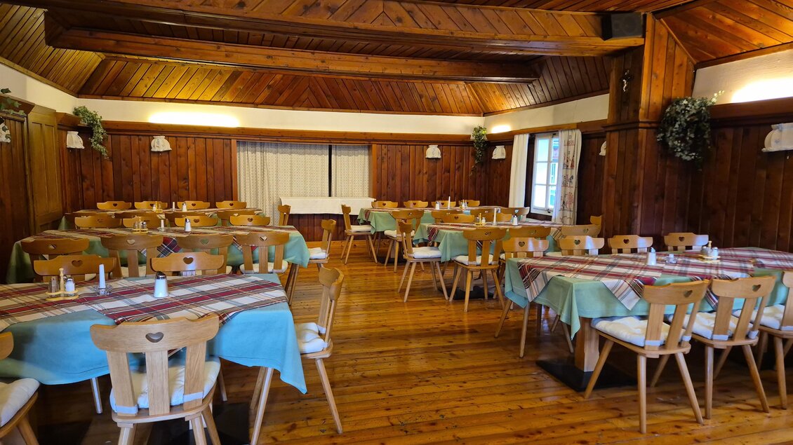 Ein gemütlicher Speisesaal mit Holzverkleidung und rustikalen Tischen. Die Tische sind gedeckt und laden zum Essen ein. | © TV Murau