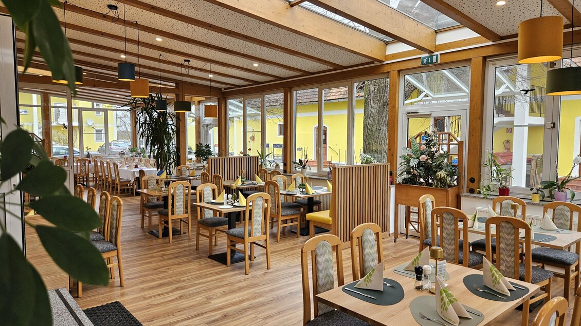 Ein gemütliches Restaurant mit vielen Tischen und Stühlen. Große Fenster sorgen für viel Tageslicht und eine angenehme Atmosphäre.