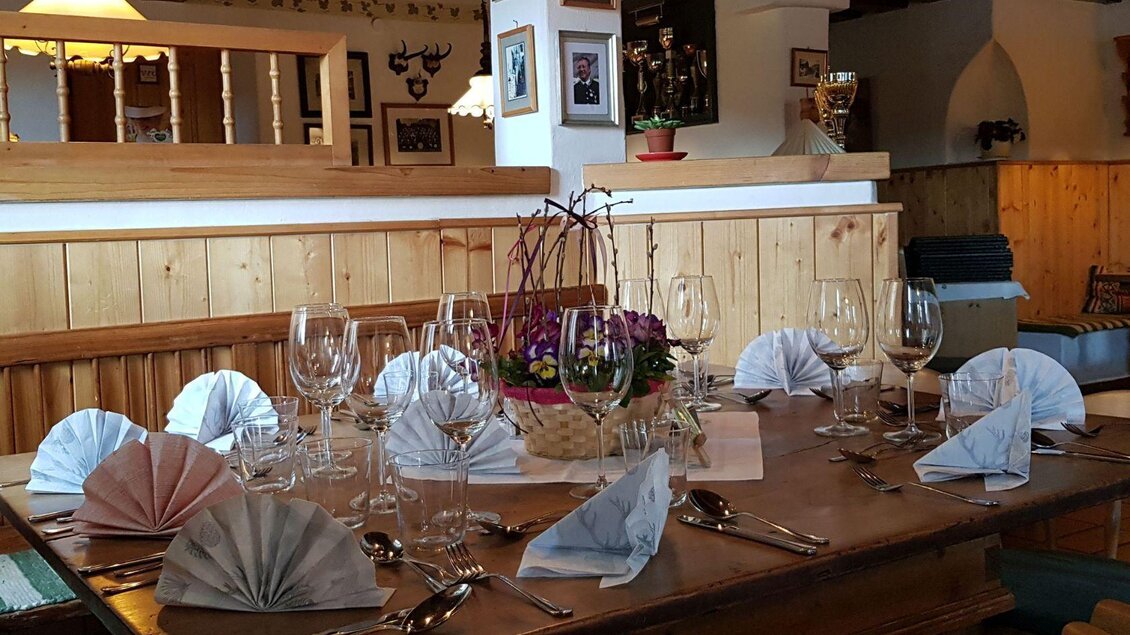 Ein elegant gedeckter Tisch mit Gläsern und kunstvoll gefalteten Servietten. In der Mitte steht ein dekorativer Blumenstrauß. | © Stephanie Bor