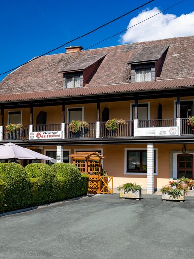 Außenansicht des Gasthofs Herlwirt in Ligist, Steiermark, mit Balkon, Blumenschmuck und Vorplatz. | © TV Region Graz - Harry Schiffer