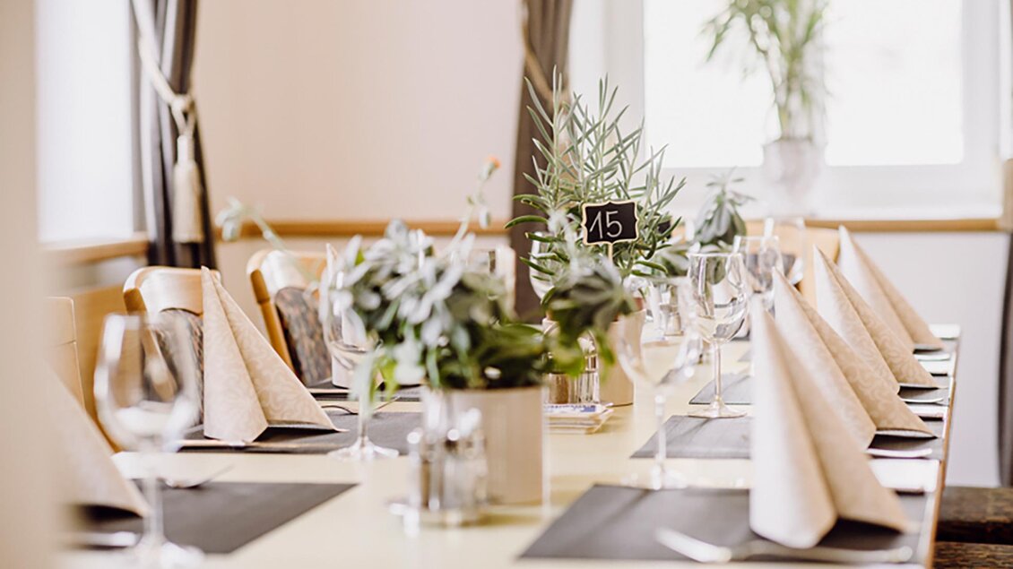 Ein elegant gedeckter Tisch mit weinfarbenen Stoffservietten und Blumen. Der Tisch ist für eine Feier vorbereitet und hat eine charmante Atmosphäre. | © Gasthof Landseele