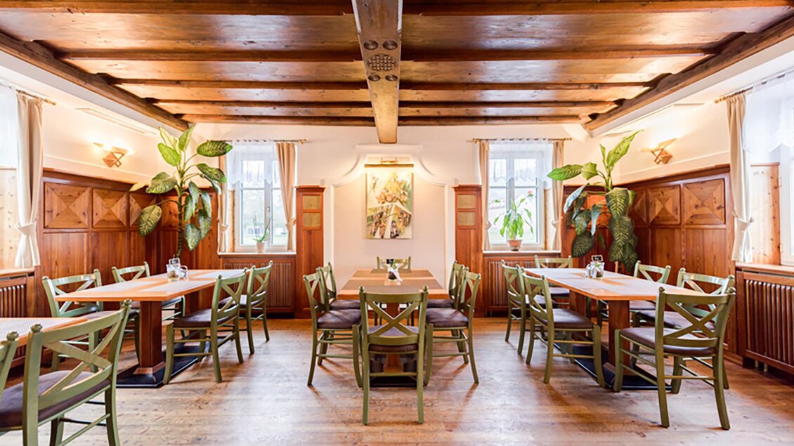 Ein einladendes Restaurant mit Holzboden und rustikalen Tischen. Große Fenster lassen viel Licht hereinfliessen und Pflanzen sorgen für eine angenehme Atmosphäre. | © Gasthof Landseele