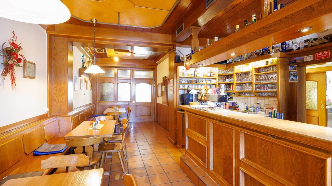 Thekenbereich im Gasthaus Muralter in Voitsberg mit Holzvertäfelung, Sitzplätzen und Regalen mit Getränken. | © TV Region Graz-Harry Schiffer