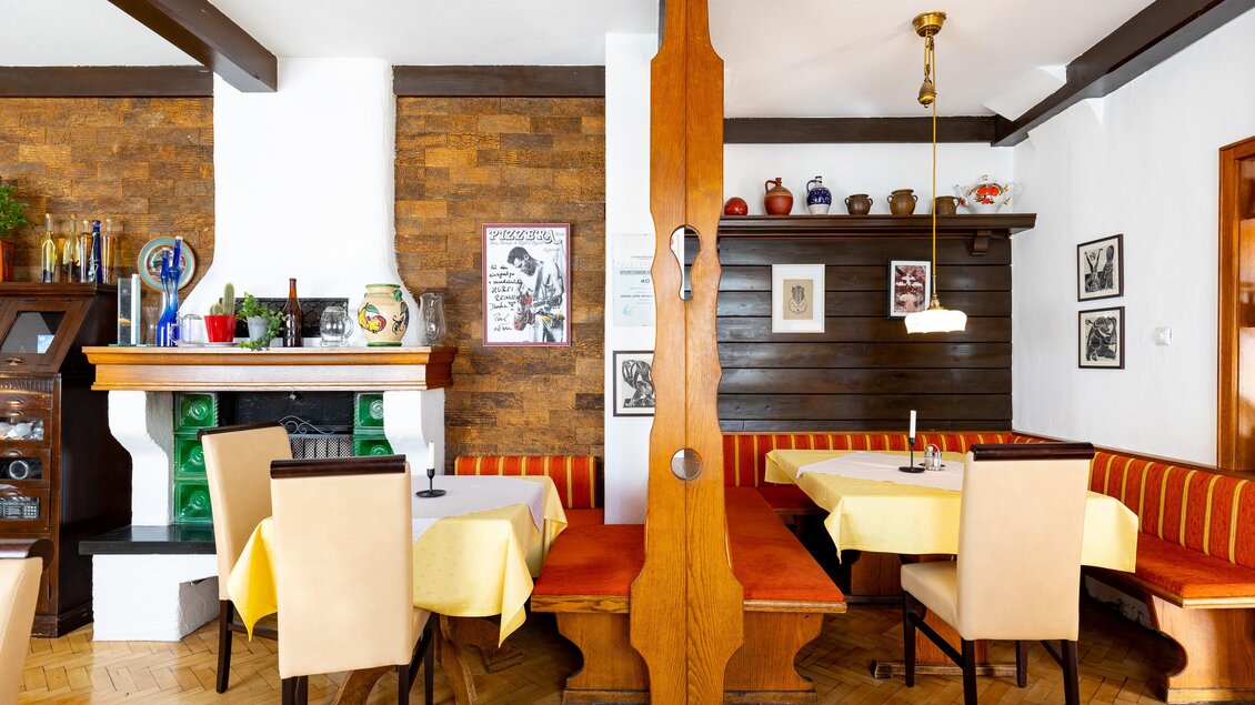 Traditionelle Gaststube im Gasthof Reinisch mit Holzbänken, gedeckten Tischen und Kachelofen in Köflach.  | © TV Region Graz - Harry Schiffer