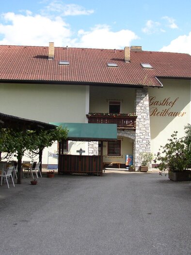 A cozy inn with a large, covered outdoor area. Surrounded by trees, it offers an inviting atmosphere in a rural setting.