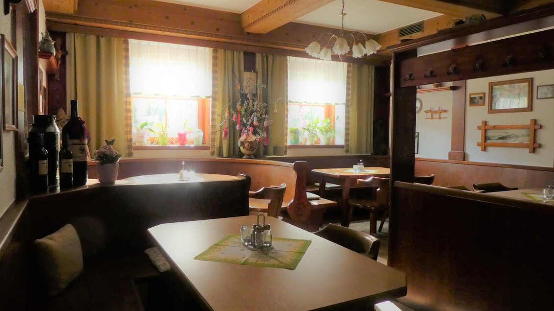 Ein gemütliches Restaurant mit Holzmöbeln und warmem Licht. Die Fenster sind freundlich dekoriert und schaffen eine einladende Atmosphäre.