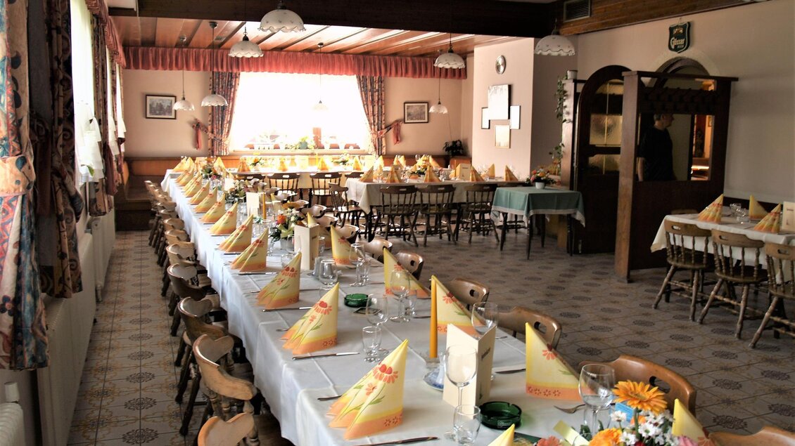 Ein eleganter Speisesaal mit langen Tischen und dekorierten Servietten. Die Atmosphäre ist einladend und festlich.