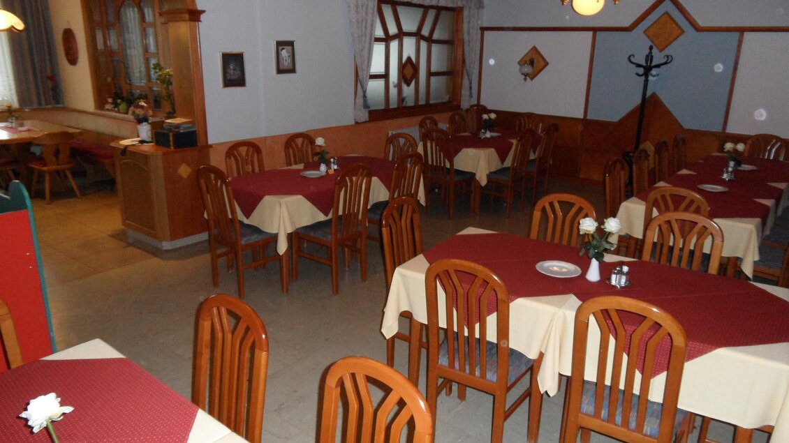 Ein gemütliches Restaurant mit Holztischen und Stühlen. Die Tische sind mit roten Tischdecken und weißen Rosen dekoriert. | © SAM