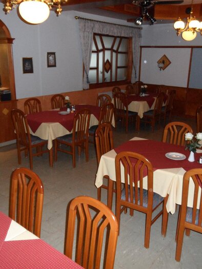 Ein gemütliches Restaurant mit Holztischen und Stühlen. Die Tische sind mit roten Tischdecken und weißen Rosen dekoriert. | © SAM