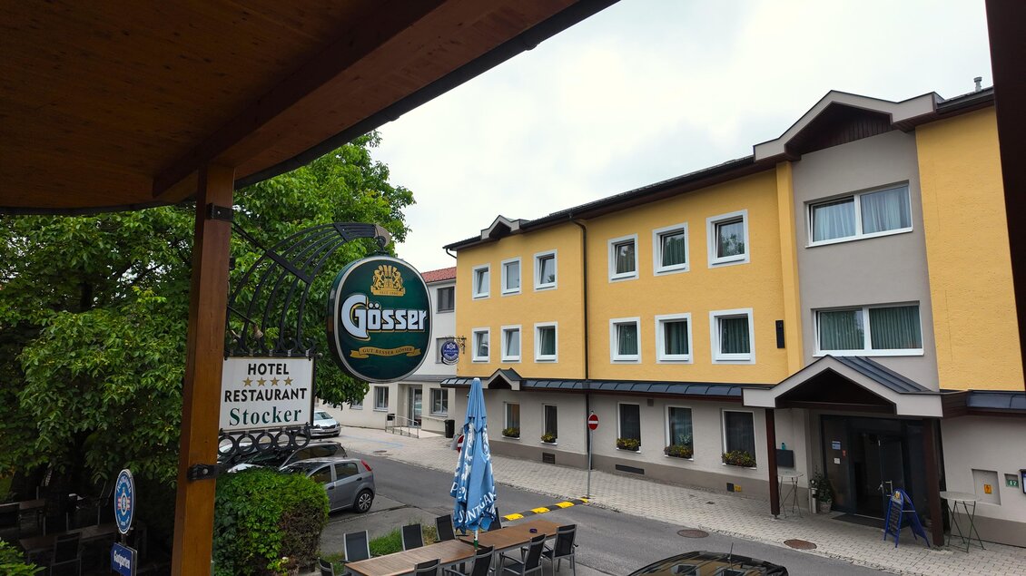 Ein Hotel mit gelber Fassade und einem Restaurant. Vor dem Gebäude stehen eine Terrasse und ein Schild mit der Aufschrift "Gösser". | © TV Hochsteiermark/Amelie Kertelits