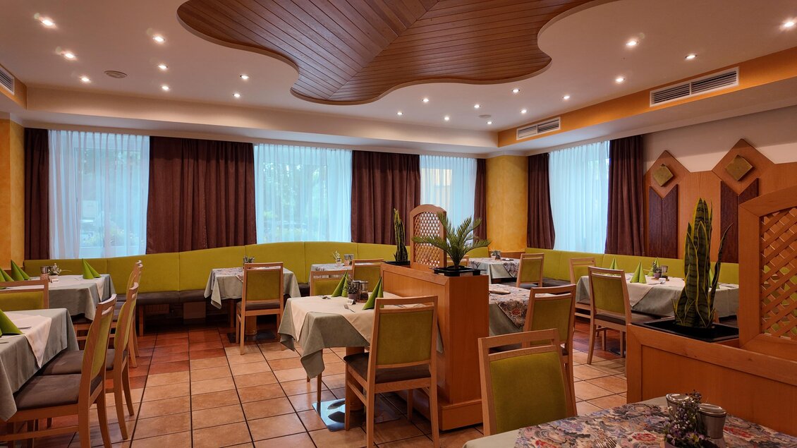 Ein elegantes Restaurant mit grünen Wänden und hellen Vorhängen. Die Tische sind ordentlich gedeckt und im Raum gibt es einige Pflanzen. | © TV Hochsteiermark/Amelie Kertelits