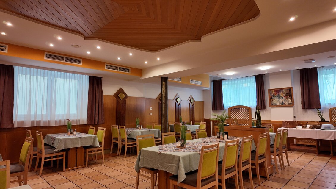 Ein gemütliches Restaurant mit Holzdecke und warmem Licht. Tische mit einfachen Tischdecken sind gleichmäßig im Raum verteilt. | © TV Hochsteiermark/Amelie Kertelits